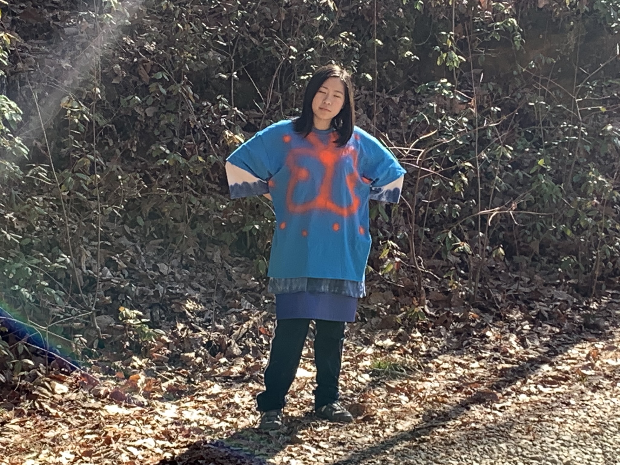 picture of asian woman closing eyes in monochromatic blue and standing in nature